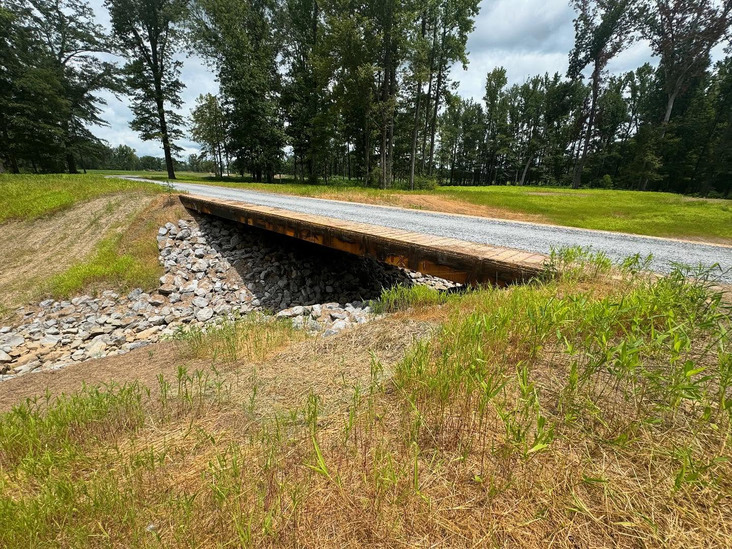 Installed bridge carrying a gravel access road over a channel