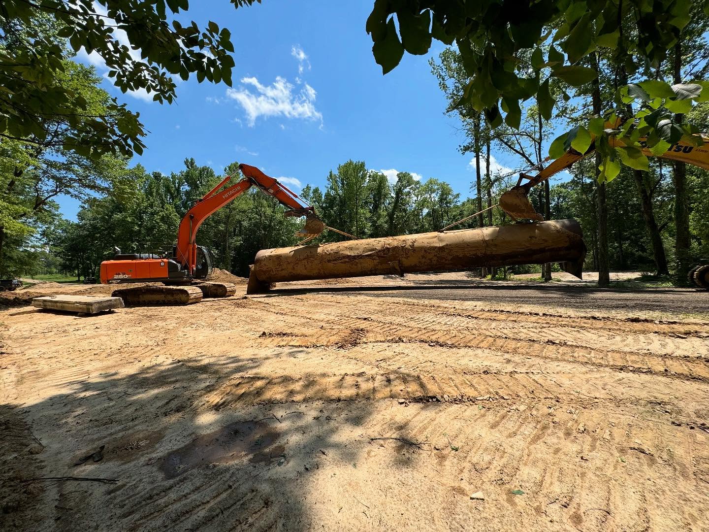 Excavators lifting a large structural piece during bridge work