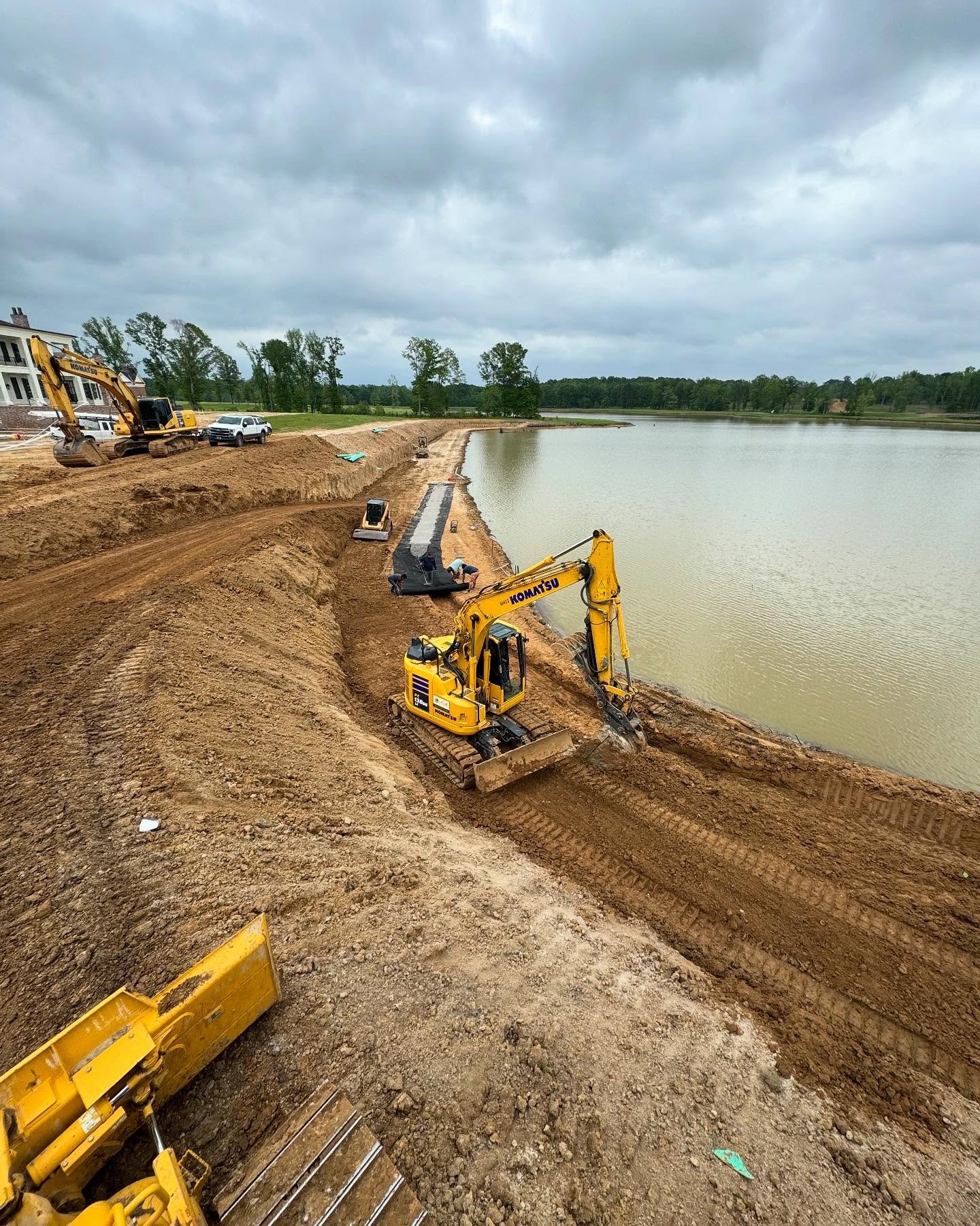 Turfscape excavators shaping a pond bank during retaining wall construction